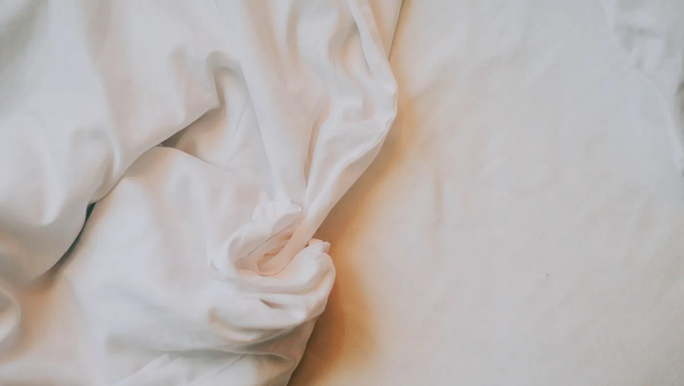 Rumpled white bed sheets in morning light