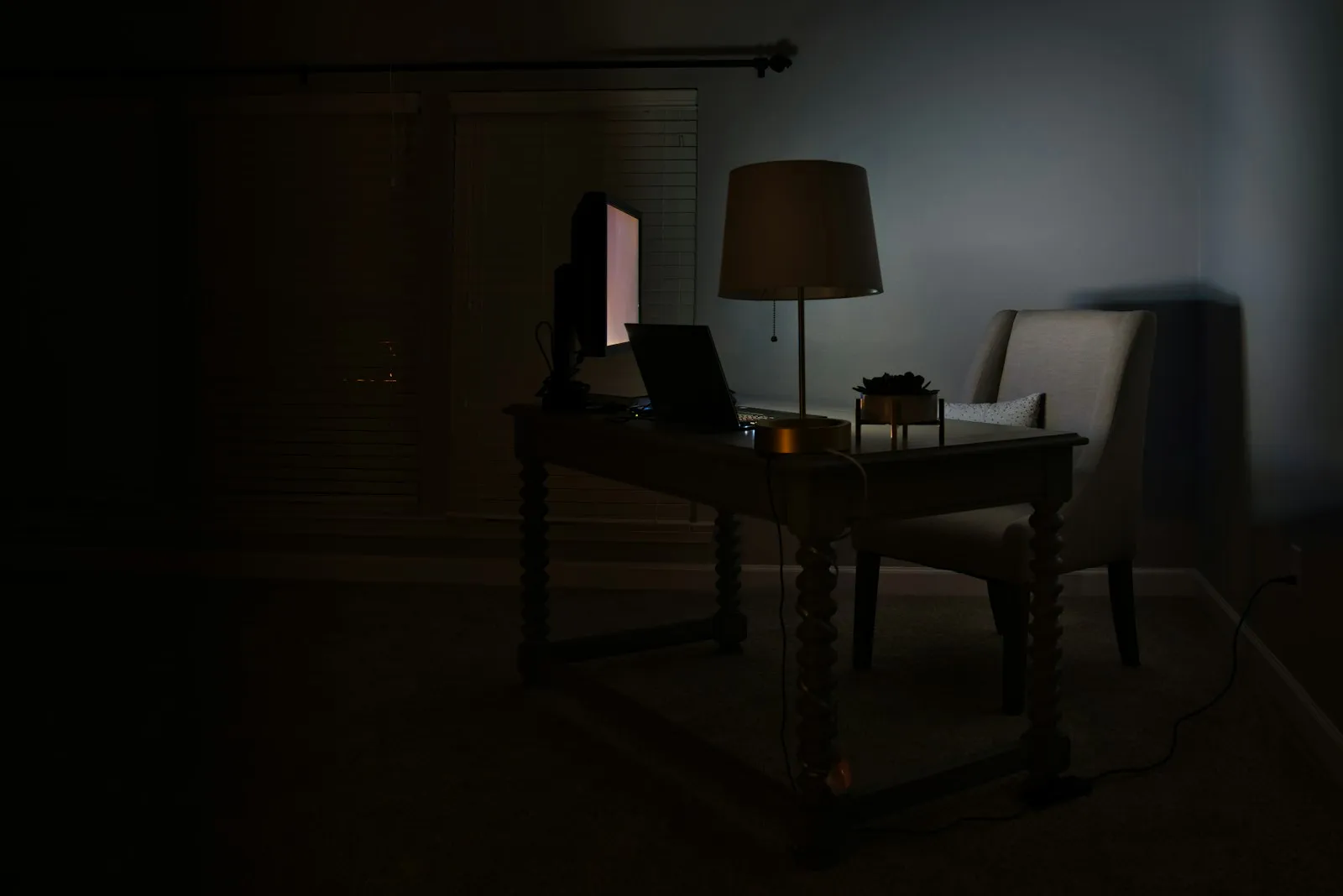 An empty desk in a dark room lit by a single lamp, the hour where long sessions happen