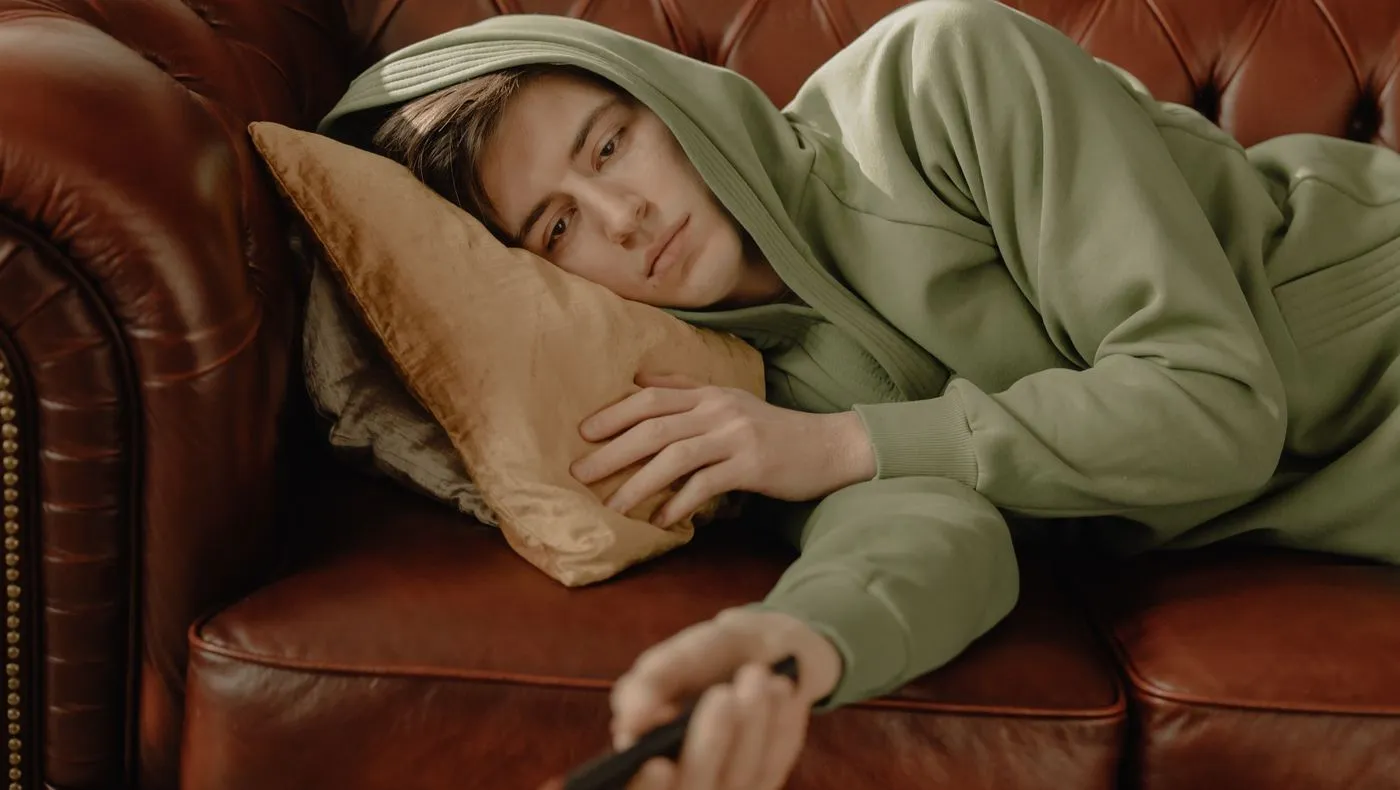A person slumped on a sofa holding a remote
