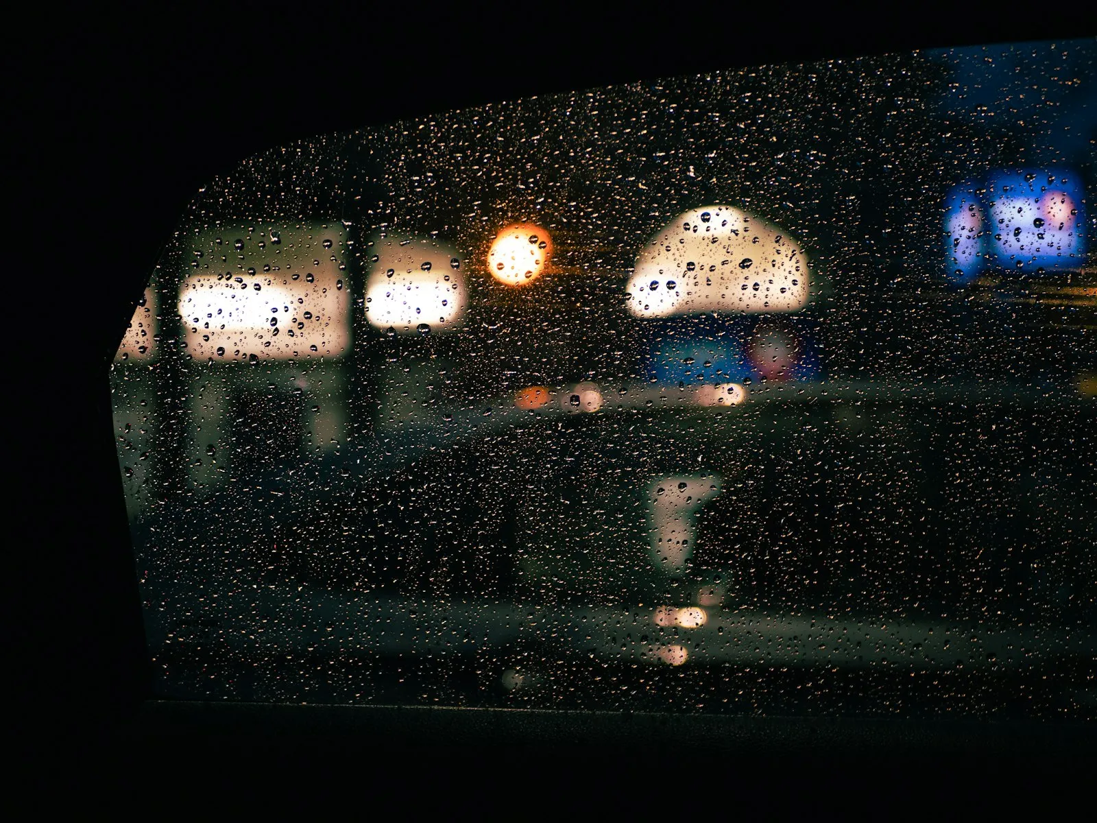 City lights blurred through rain on a window at night