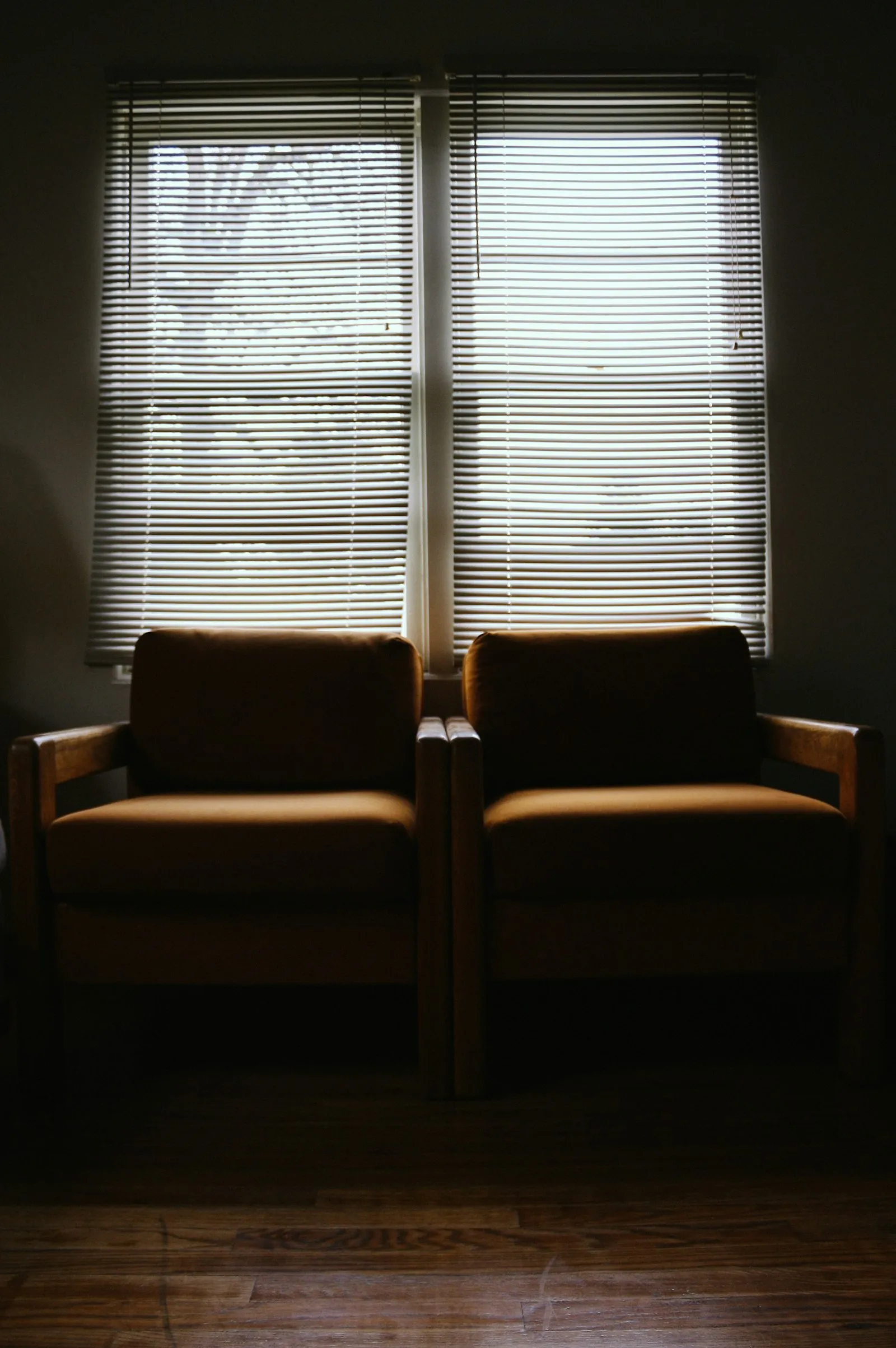 Two armchairs facing each other in a quiet room with shuttered windows
