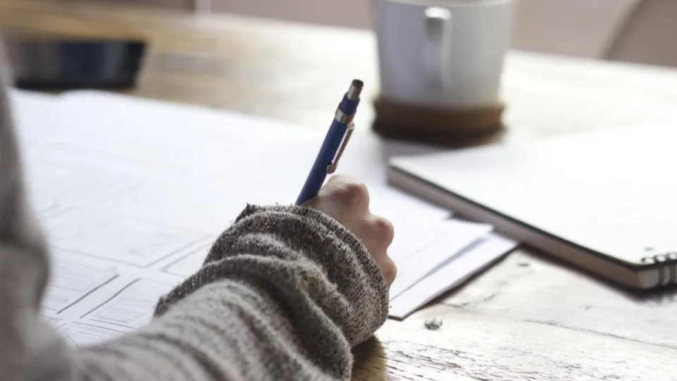 A person writing in a notebook at a desk