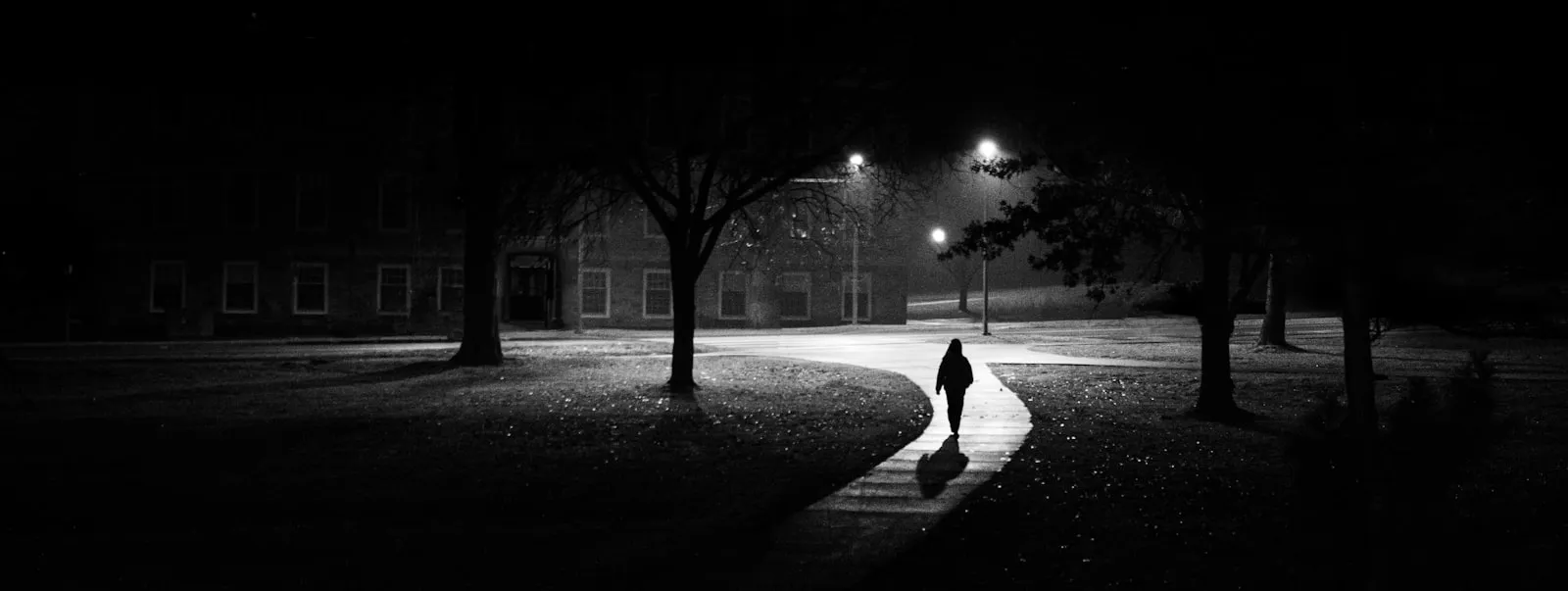 A lone figure walking down an empty street at night
