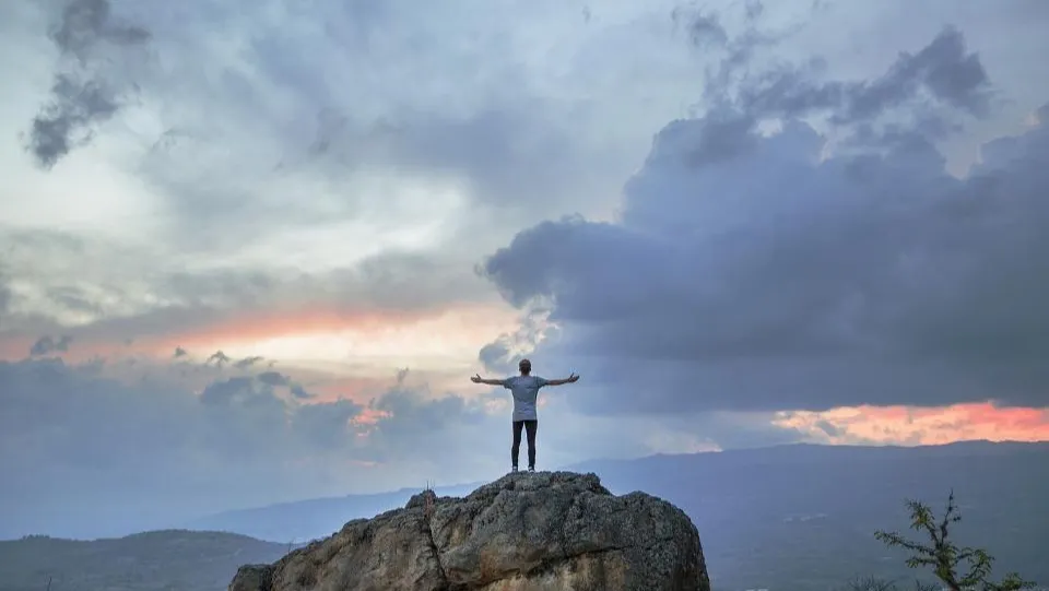 A man standing on a rock above the clouds