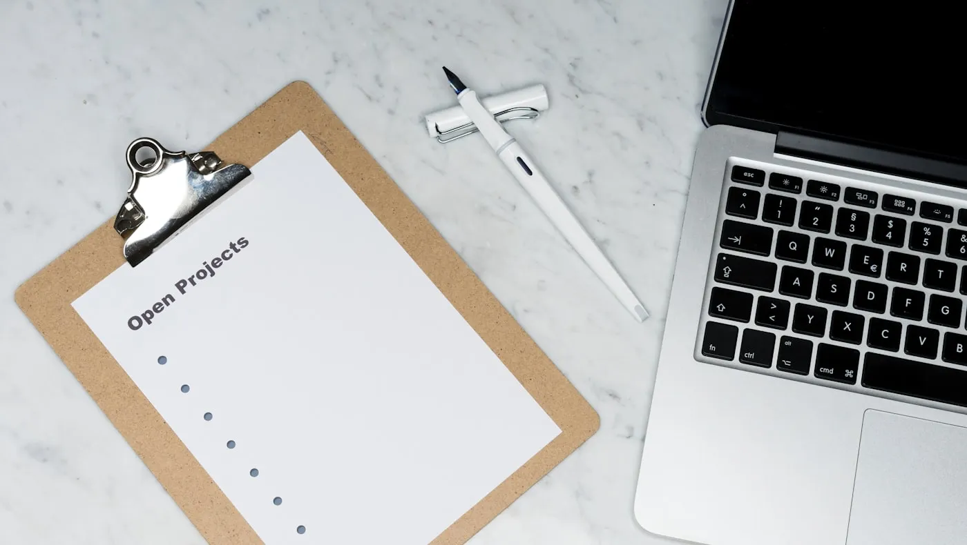 A clipboard with a blank checklist beside a laptop