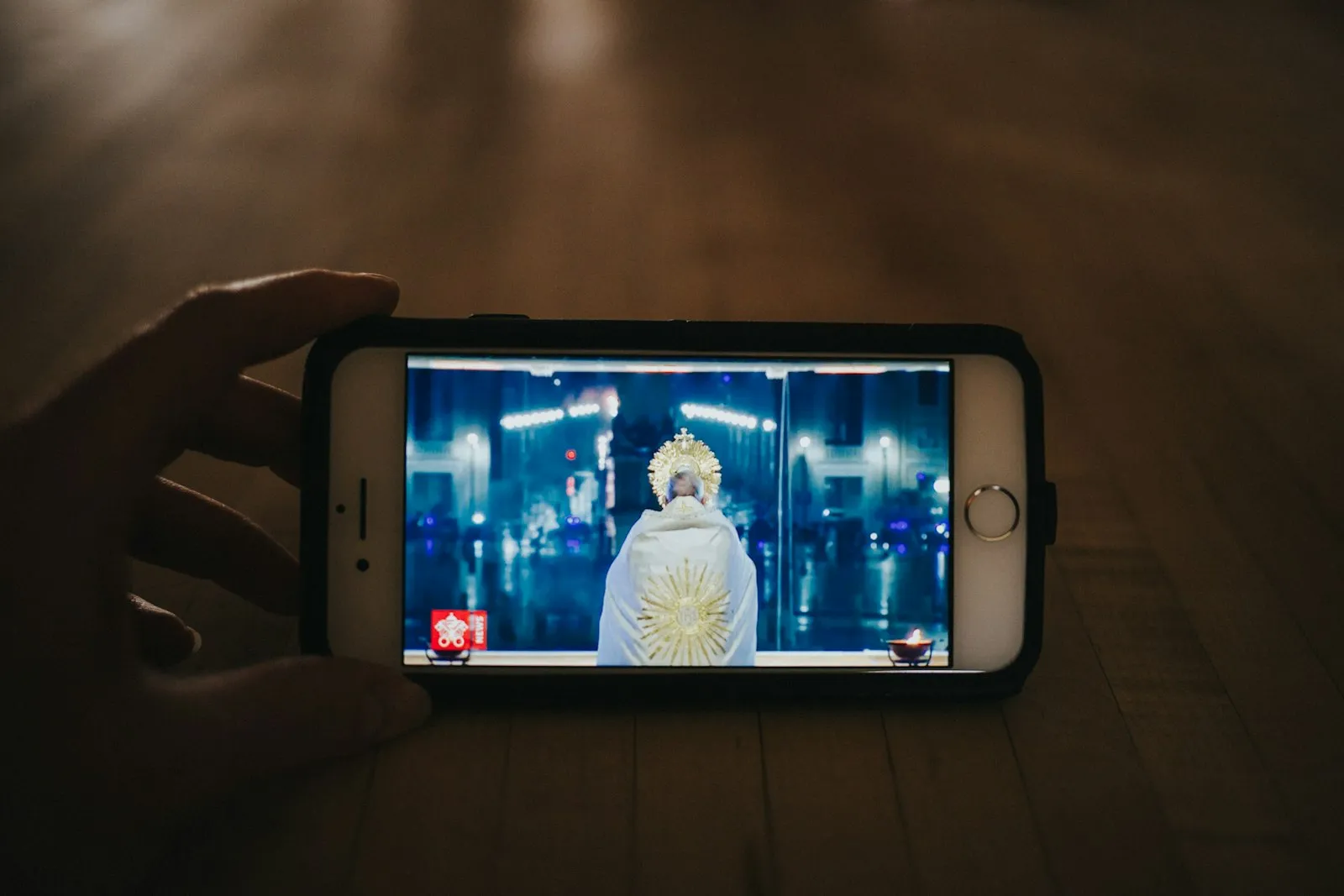 A hand holding a phone playing a video in a dark room