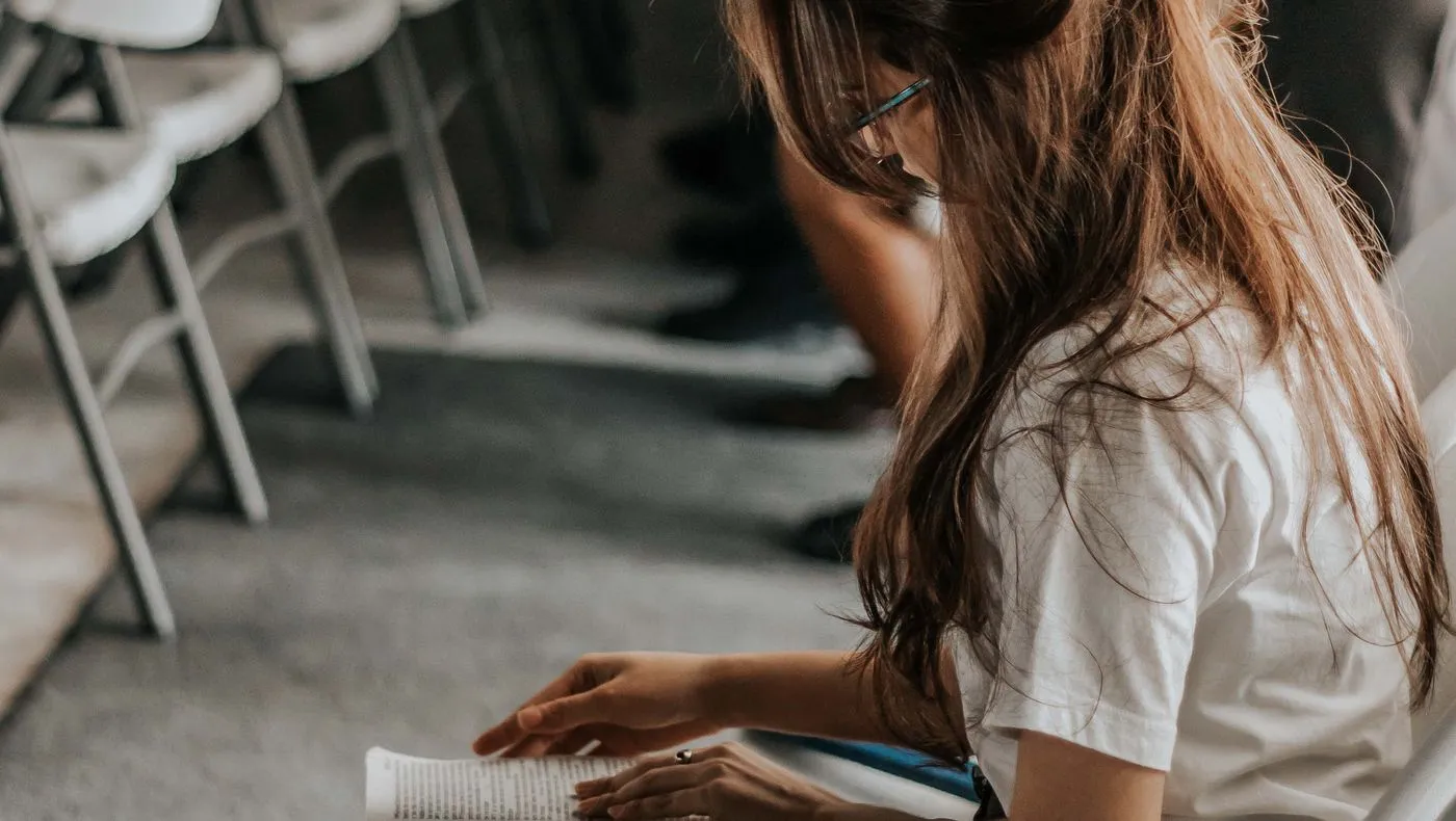 A person reading beside a window